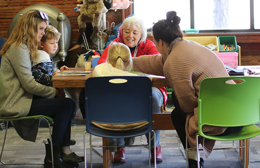 Dee Acklie, center, familiy facilitator and home visitor at DC West Elementary School, guides two moms and their kids through an activity at the Valley Public Library.
