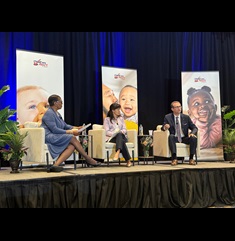 Two women and a man sit onstage at a conference during a panel discussion