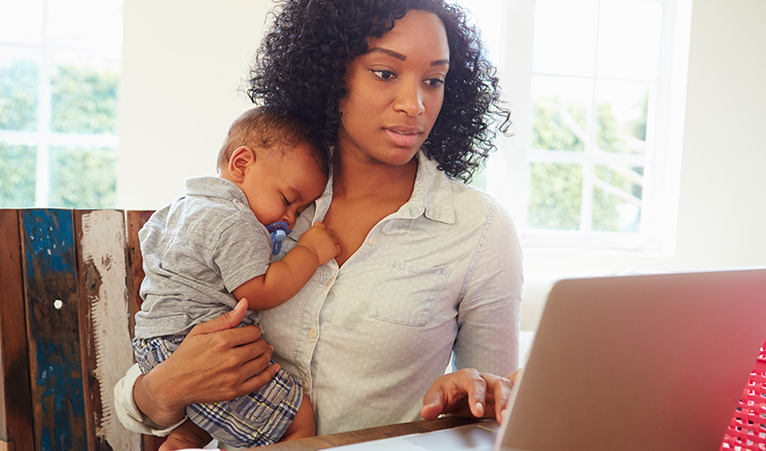 mother holding child and working at computer
