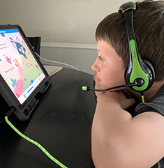 Young boy wearing headphones using computer tablet