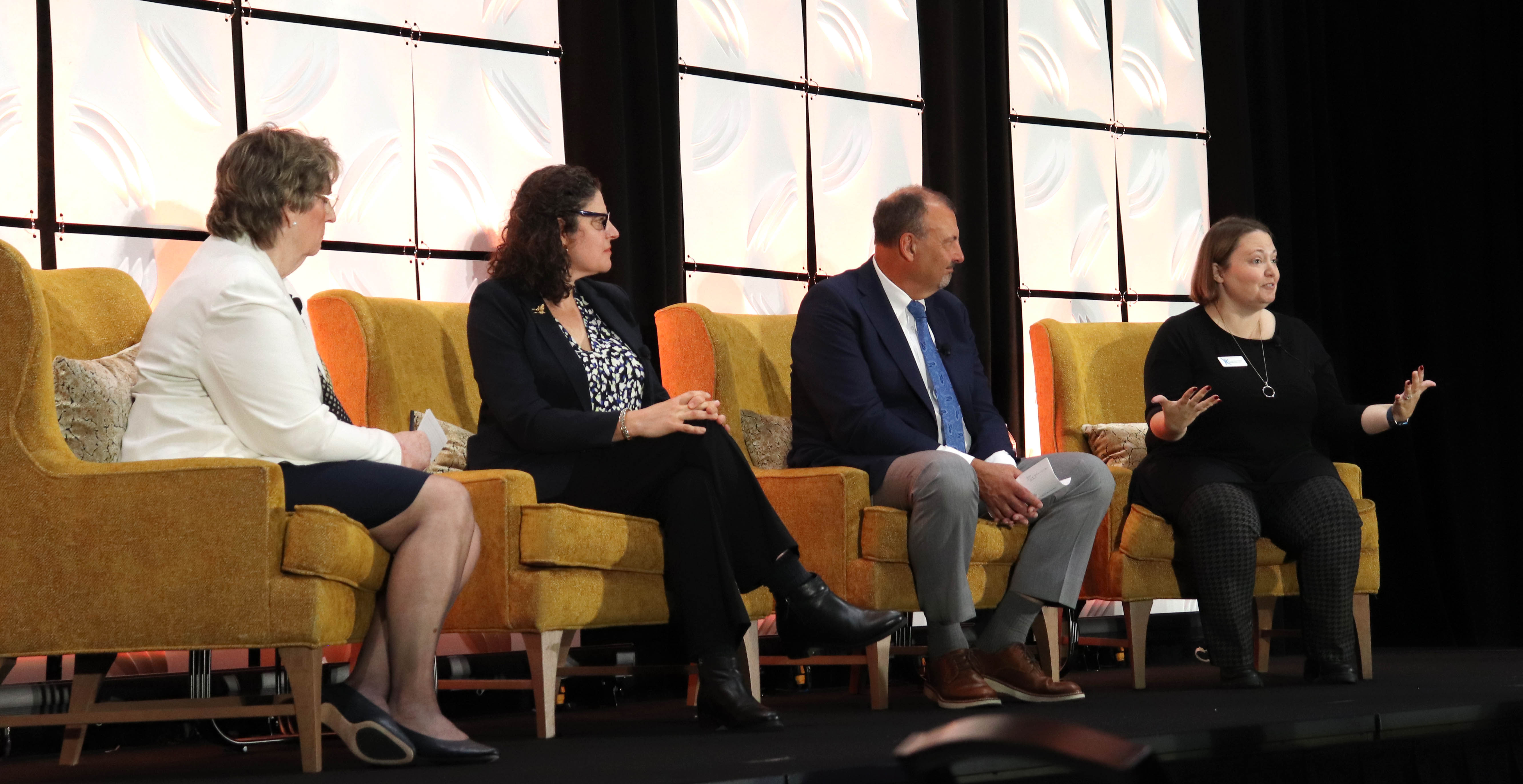 Four people on a panel sitting on chairs on a stage