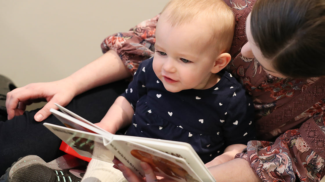 A baby being read to by a child care provider. 