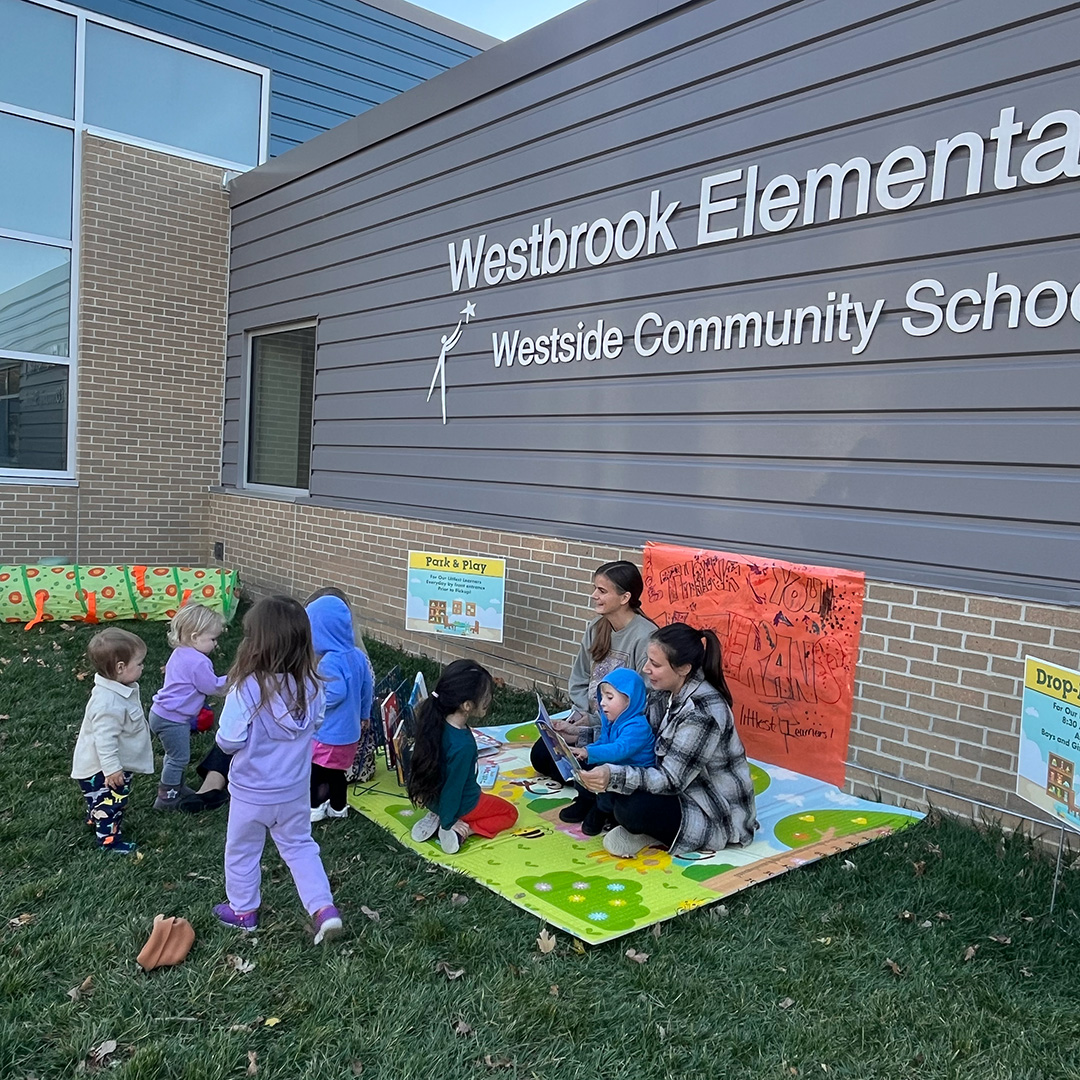 Young children playing outside a school on a blanket