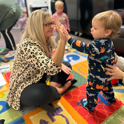 A teacher high-fives a toddler