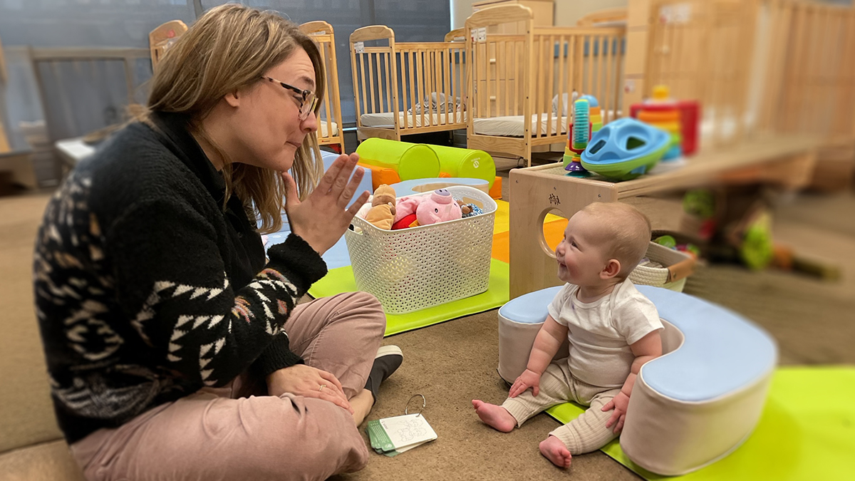 A child care provider teaches a baby sign language