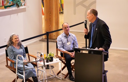 A man at a podium speaks in front of a  seated crowd