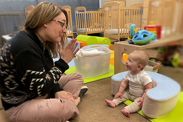 A child care provider teaches a baby sign language