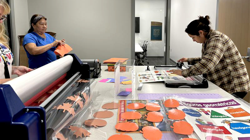 Women laminate classroom supplies