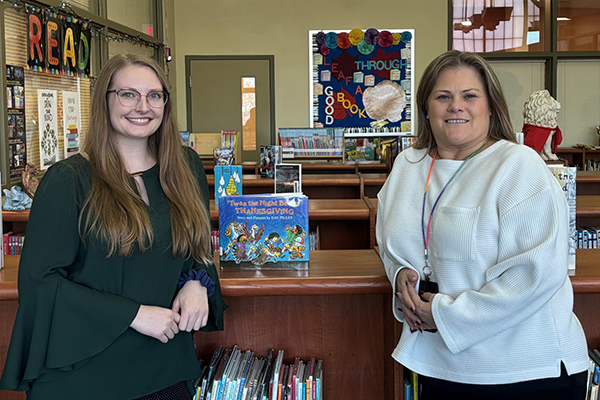 Two women standing in front of a bookcase in a school library