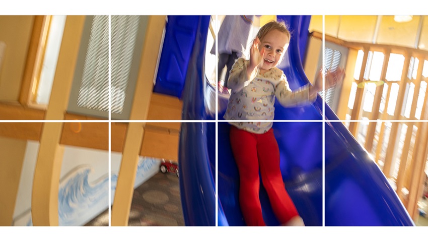 Little girl sliding down a blue slide