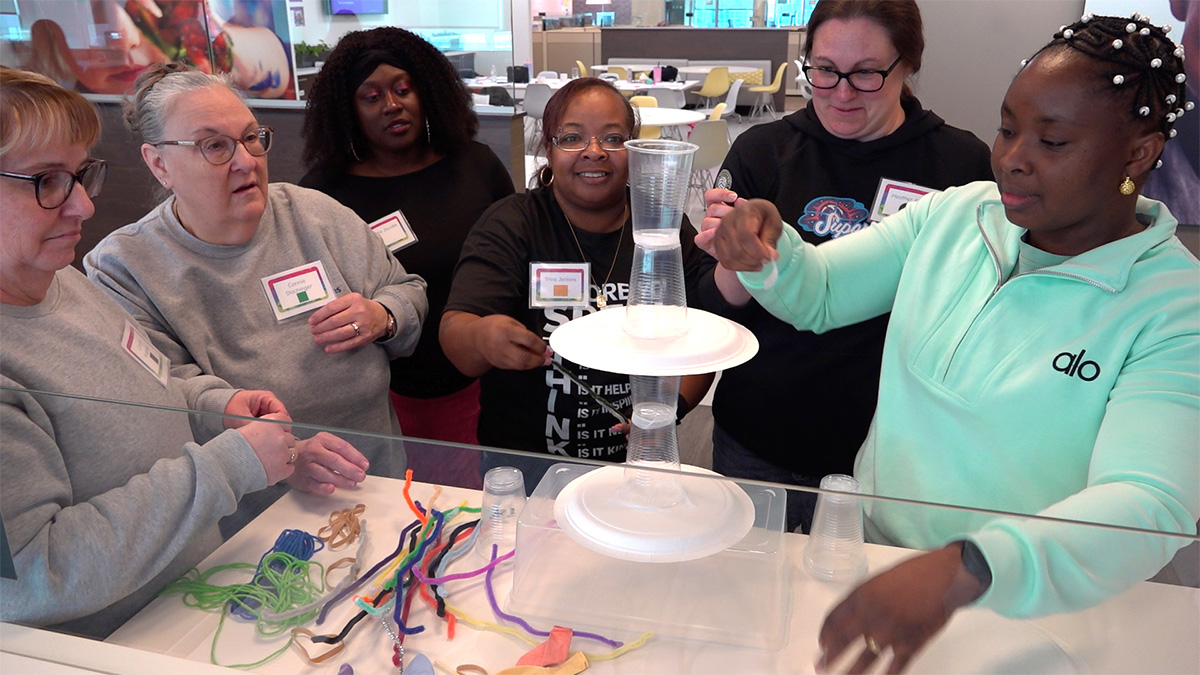 Teachers working together with paper plates and plastic cups to build a tower