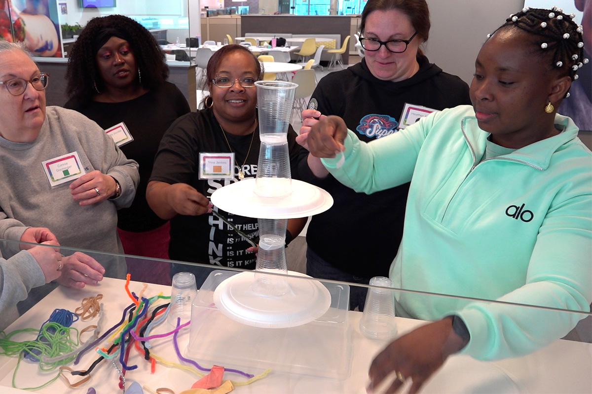 Teachers working together with paper plates and plastic cups to build a tower