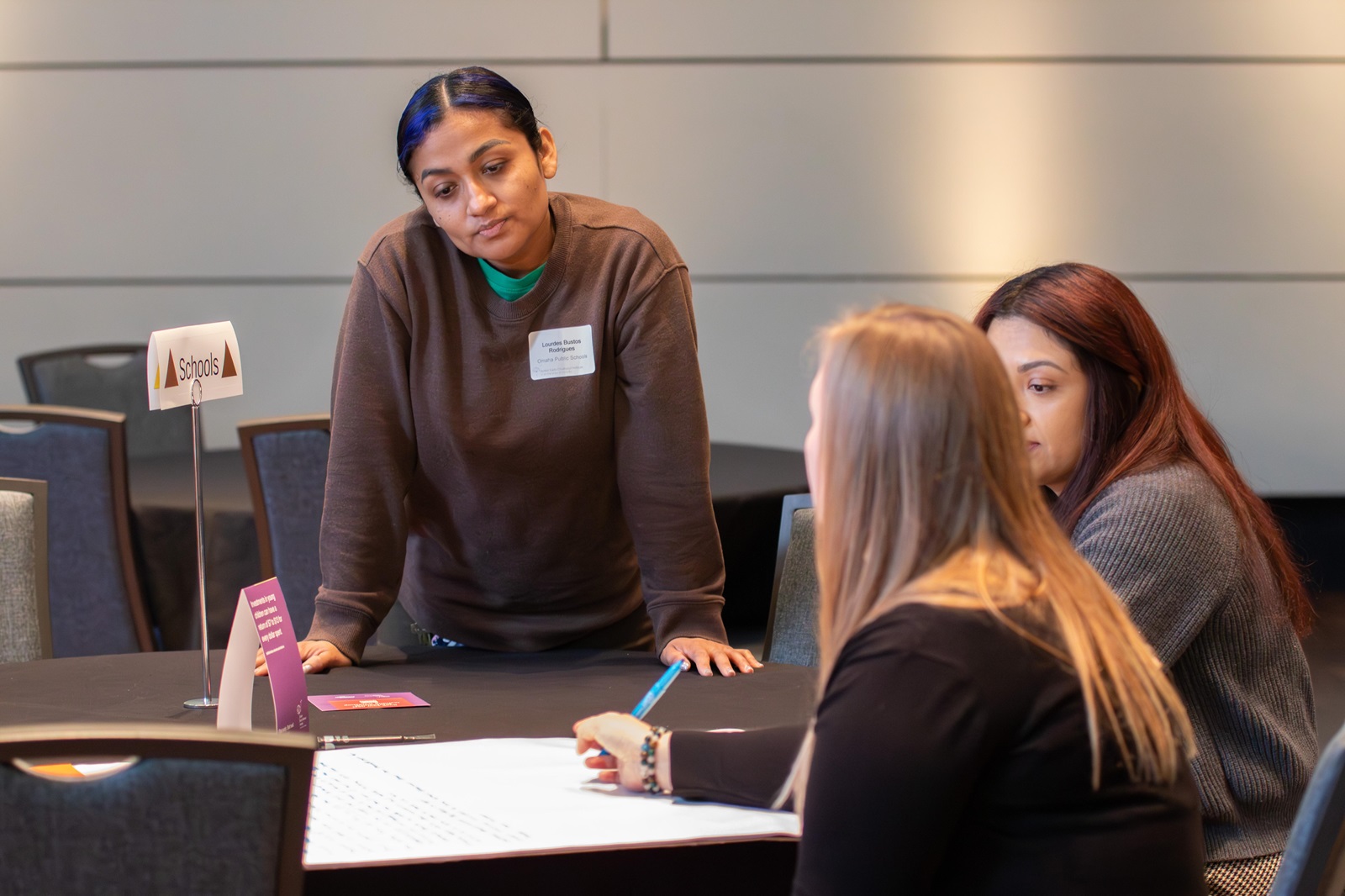 Lulu Bustos Rodriguez, a home visitor at Liberty Elementary in downtown Omaha, stands at a table with other family engagement staff at a breakout session after the 2026 Superintendents' Early Childhood Plan annual convening. 