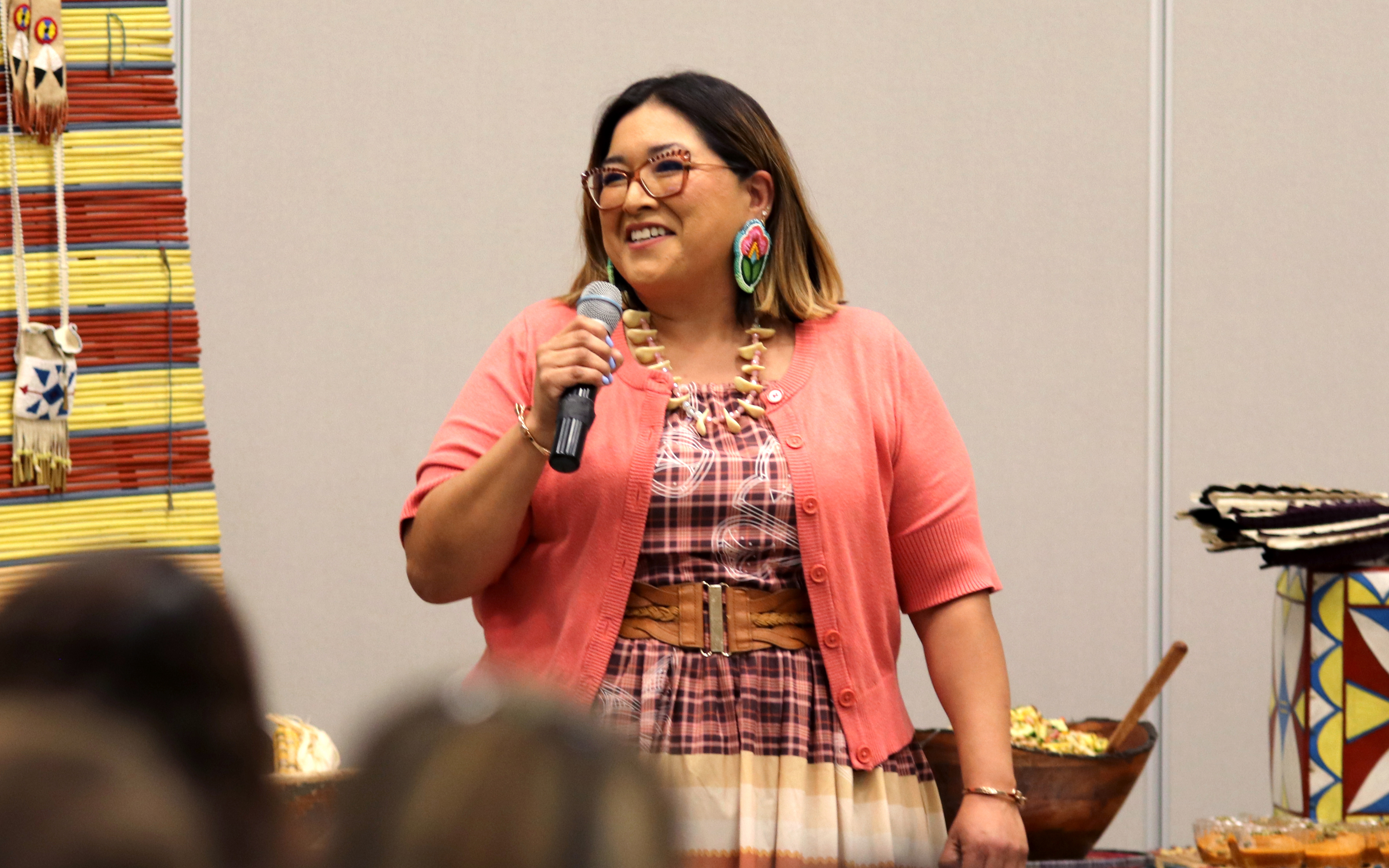 A woman with a microphone speaks in front of a room
