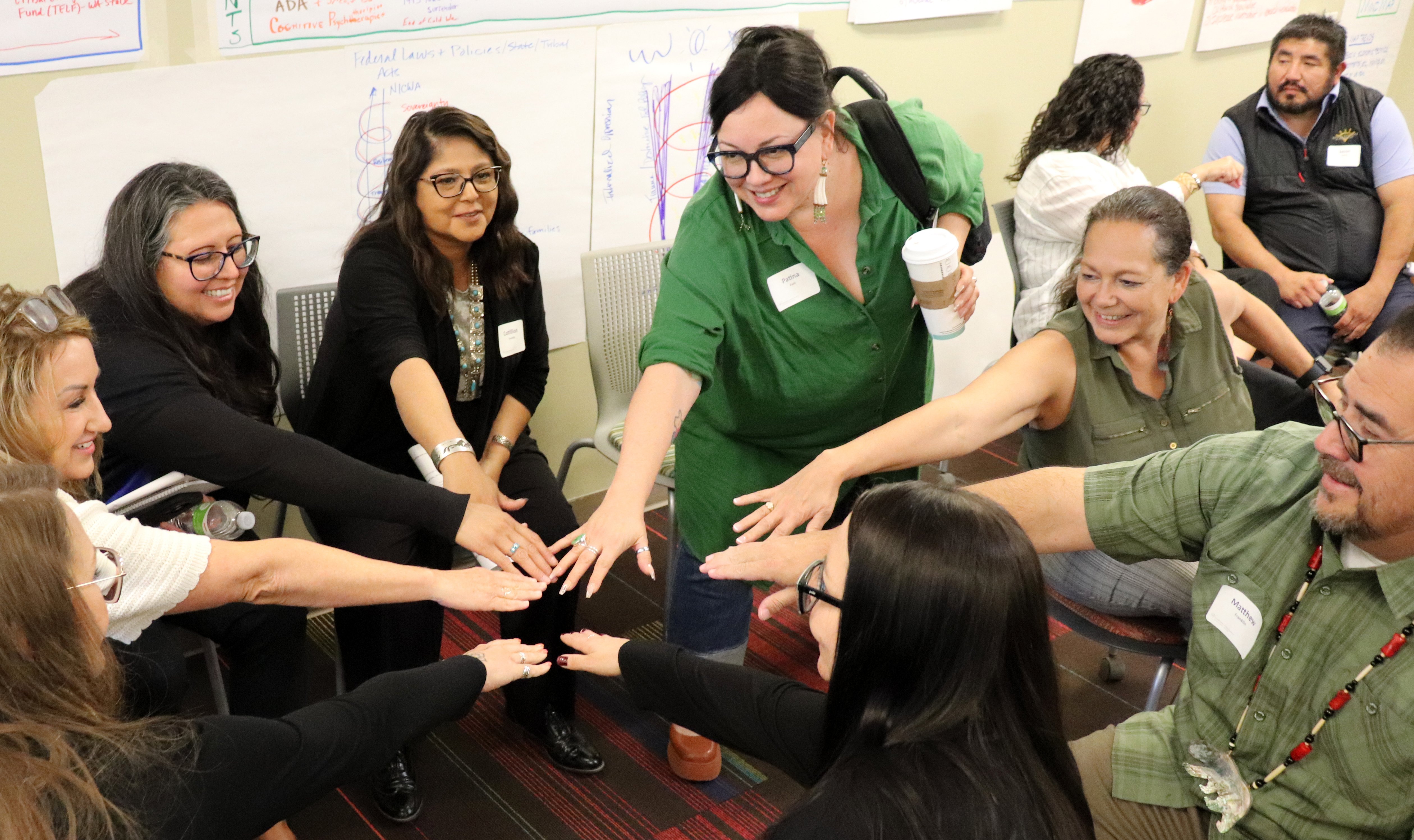 Several people in a circle put their hands together