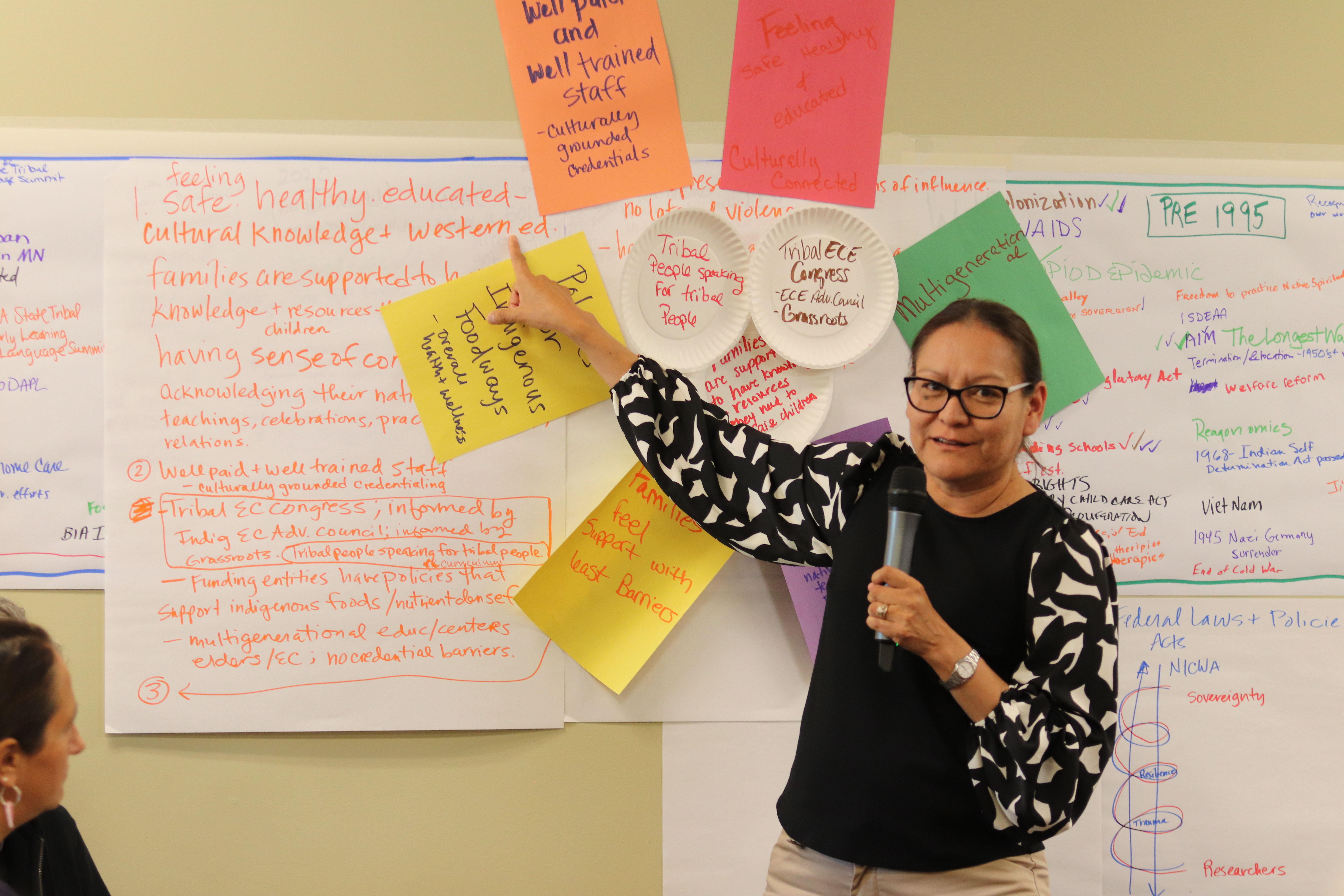 A woman stands in front of several posterboards with writing on them