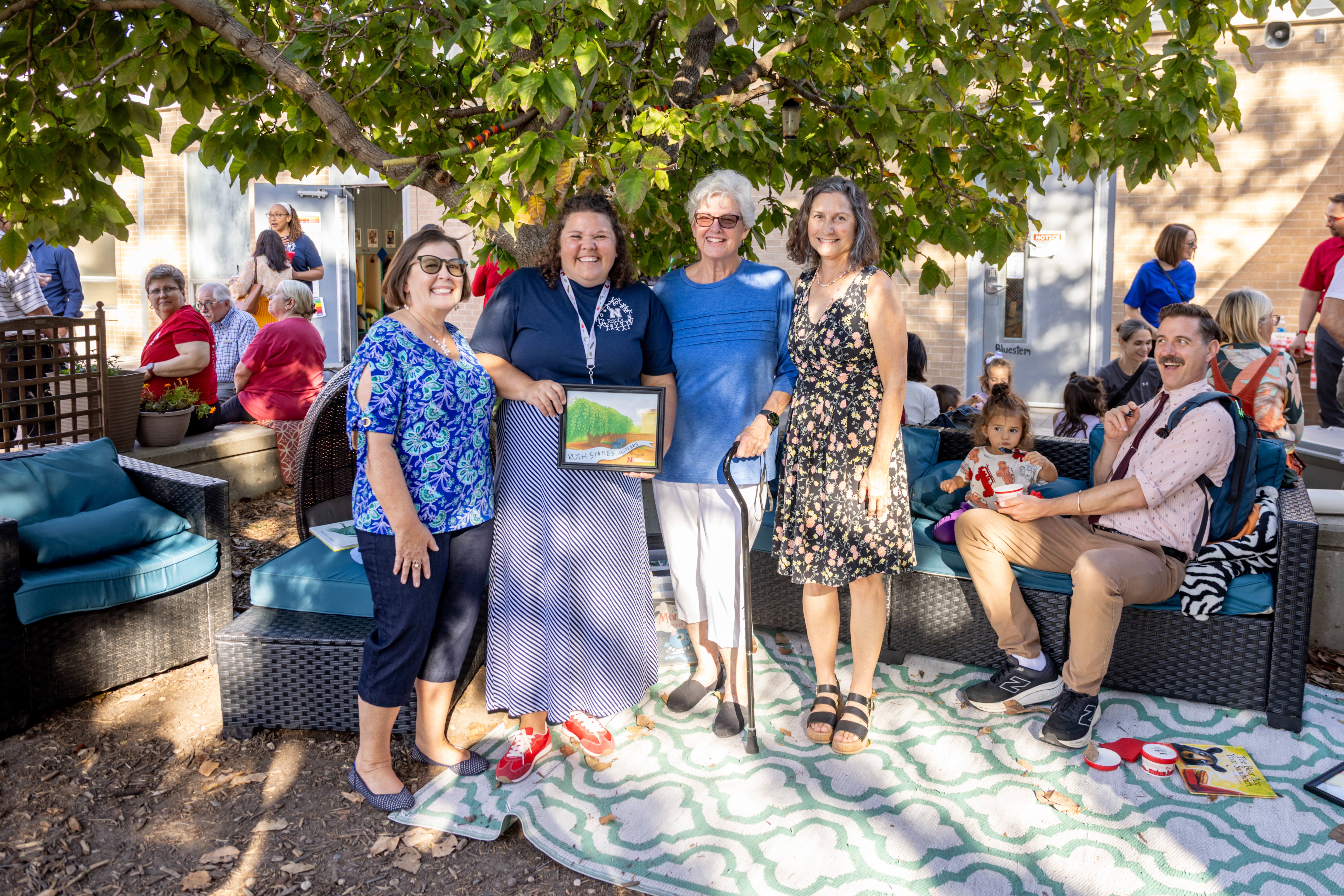Four women, the current and three former directors of the Ruth Staples Child Development Lab, pose together outside. 