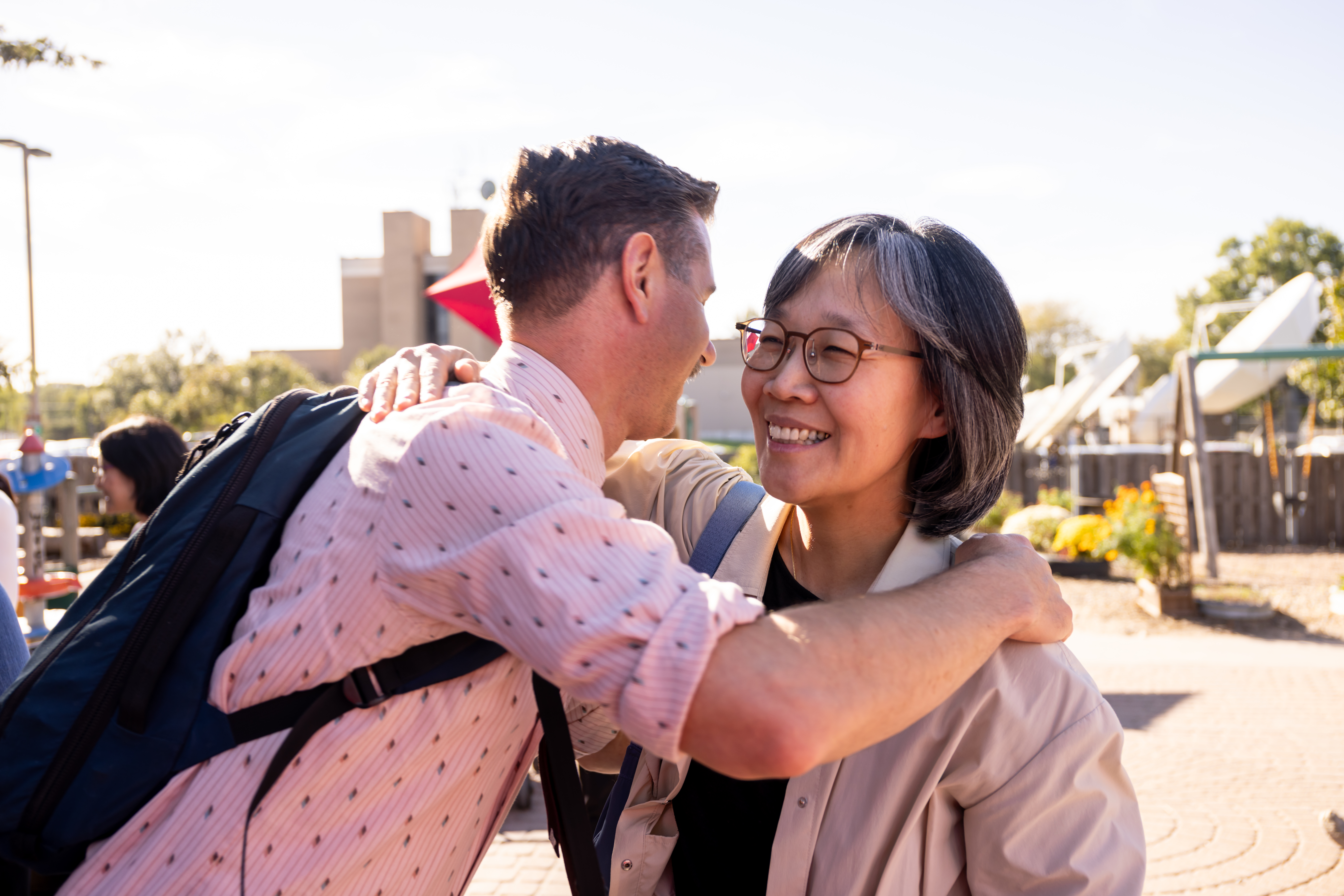 A man and a woman exchange a hug at an open house event