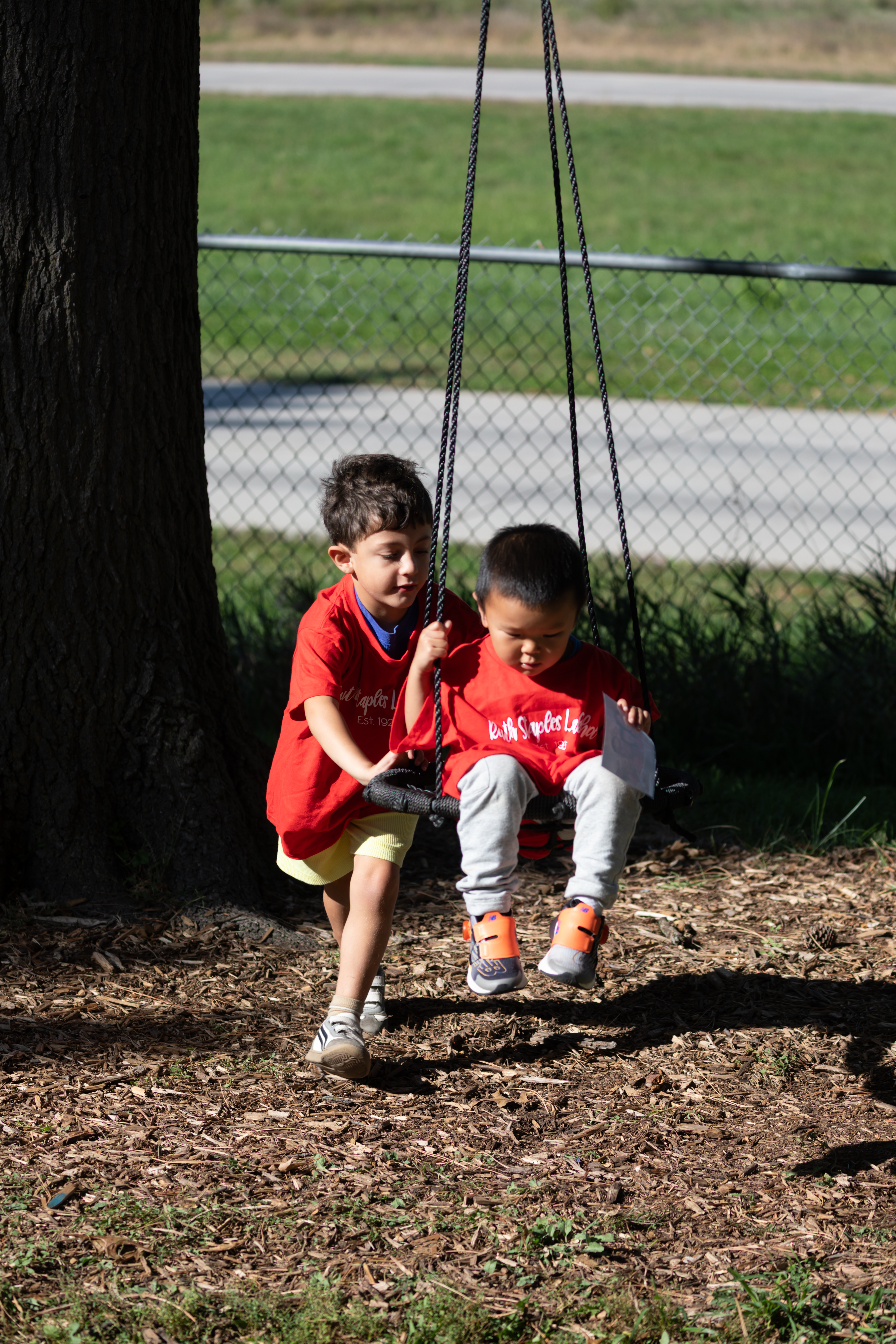 Two young children play on the swings outside the Ruth Staples Child Development Lab