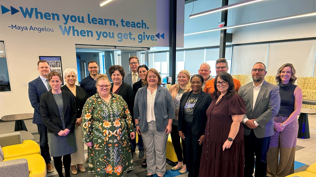 A large group standing in front of a Maya Angelou quote on a wall