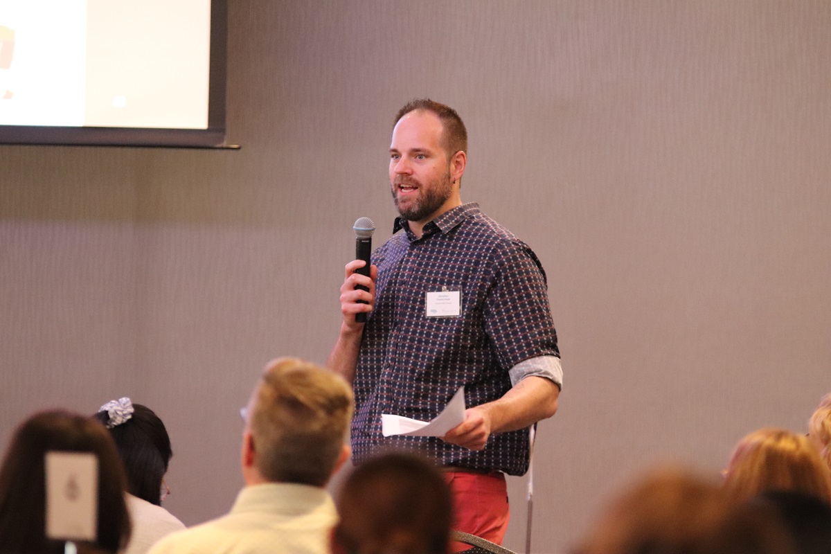 A man standing at the front of the room with a microphone