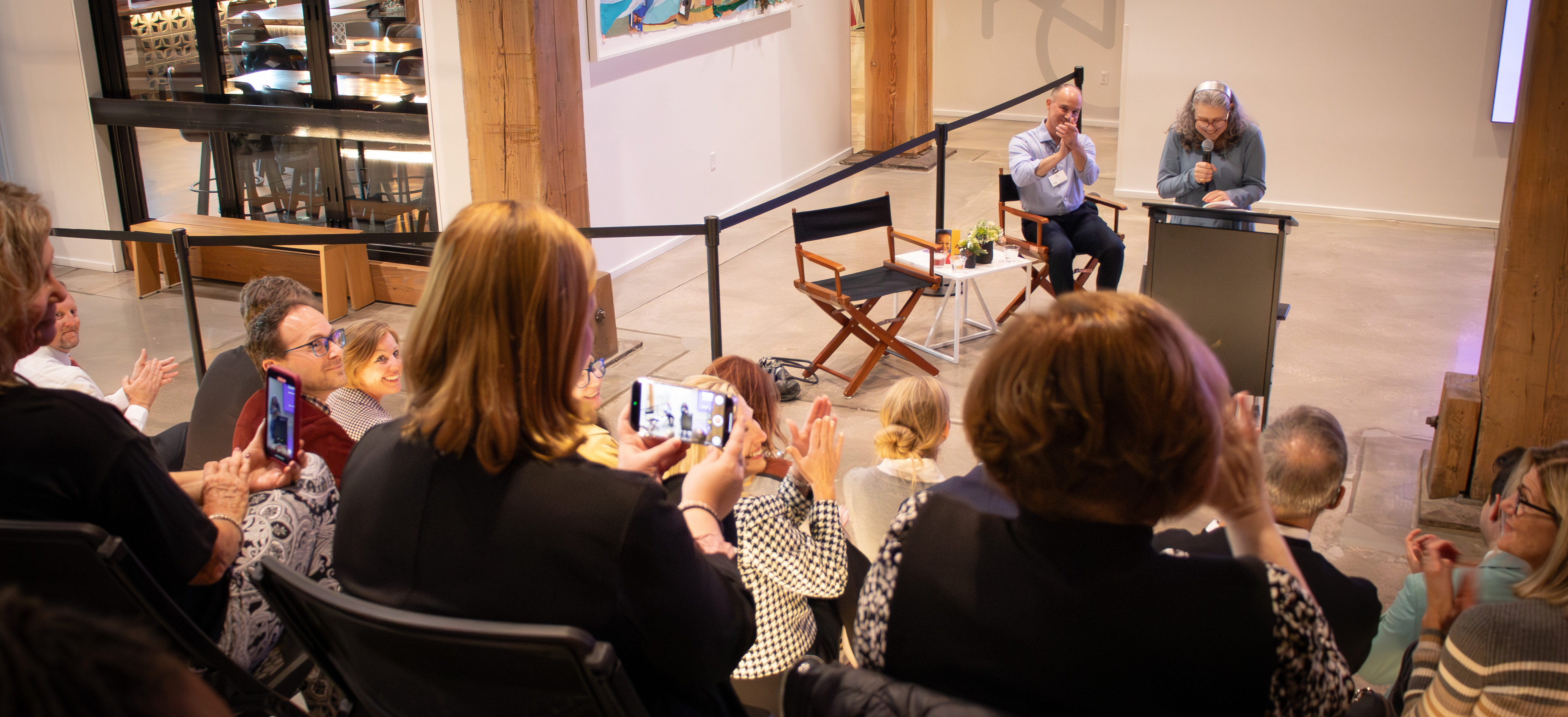 People in the crowd take photos as Debora Wisneski speaks at a reception in October 2025