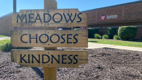 An exterior shot of Meadows Elementary School in Ralston, Neb., with a wooden sign that says, "Meadows Chooses Kindness" 