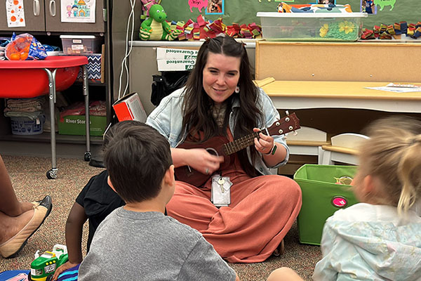 Teacher playing ukulele for students