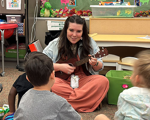 Teacher playing ukulele for students