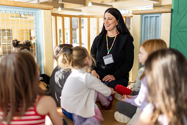 Photo of an early childhood teacher sitting surrounded by children