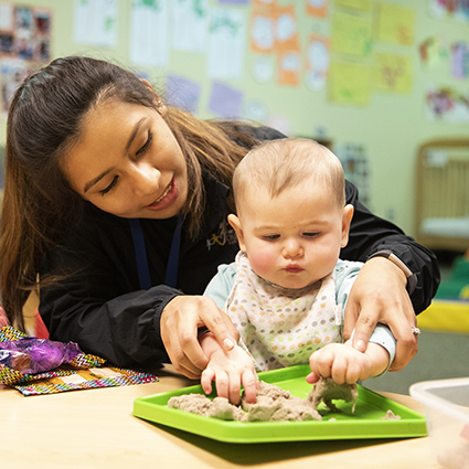 teacher helping infant with motor skills