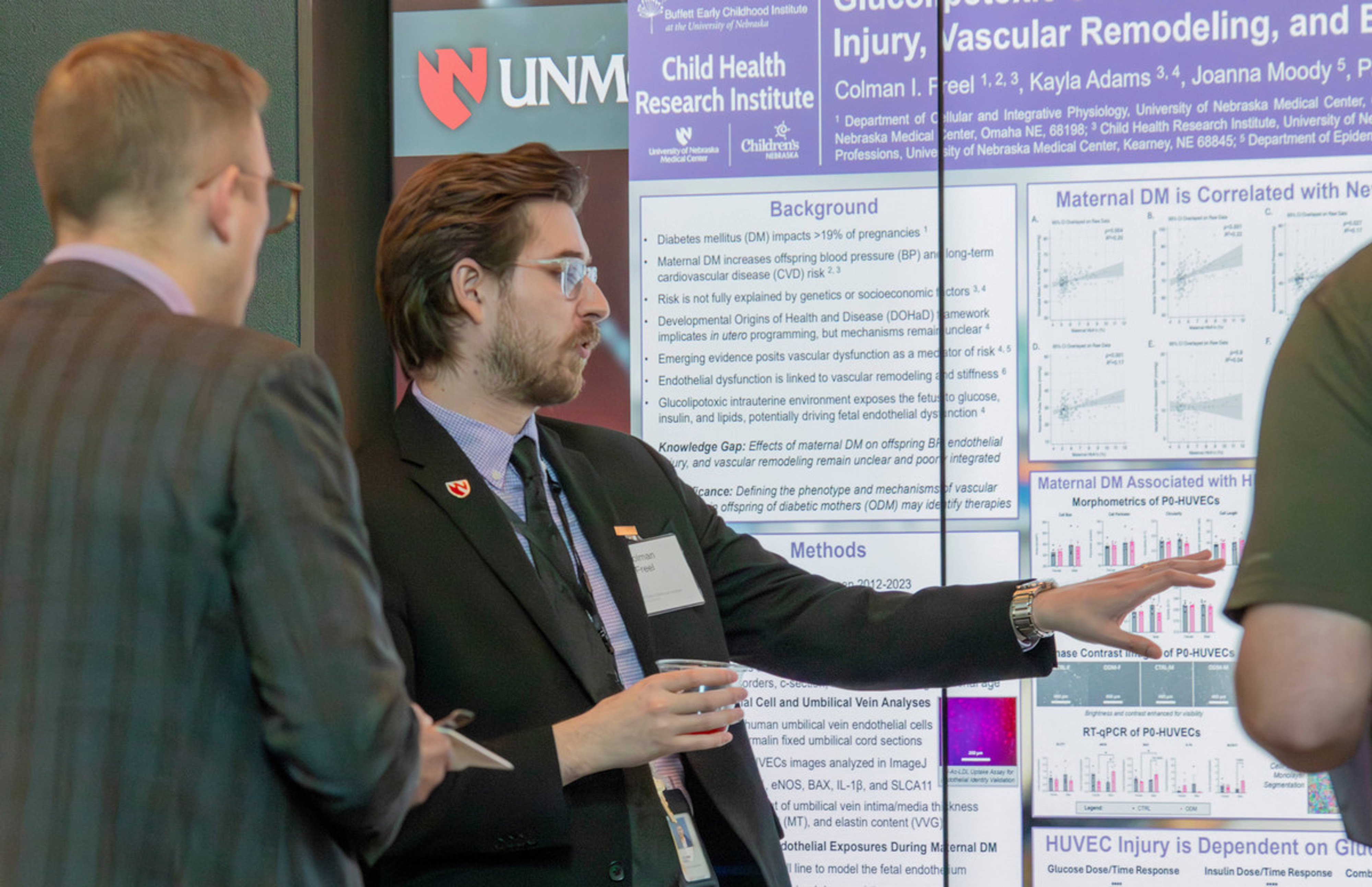 Event attendees asked UNMC Ph.D. student Colman Freel questions about his research project. The digital screen showcases his research poster.