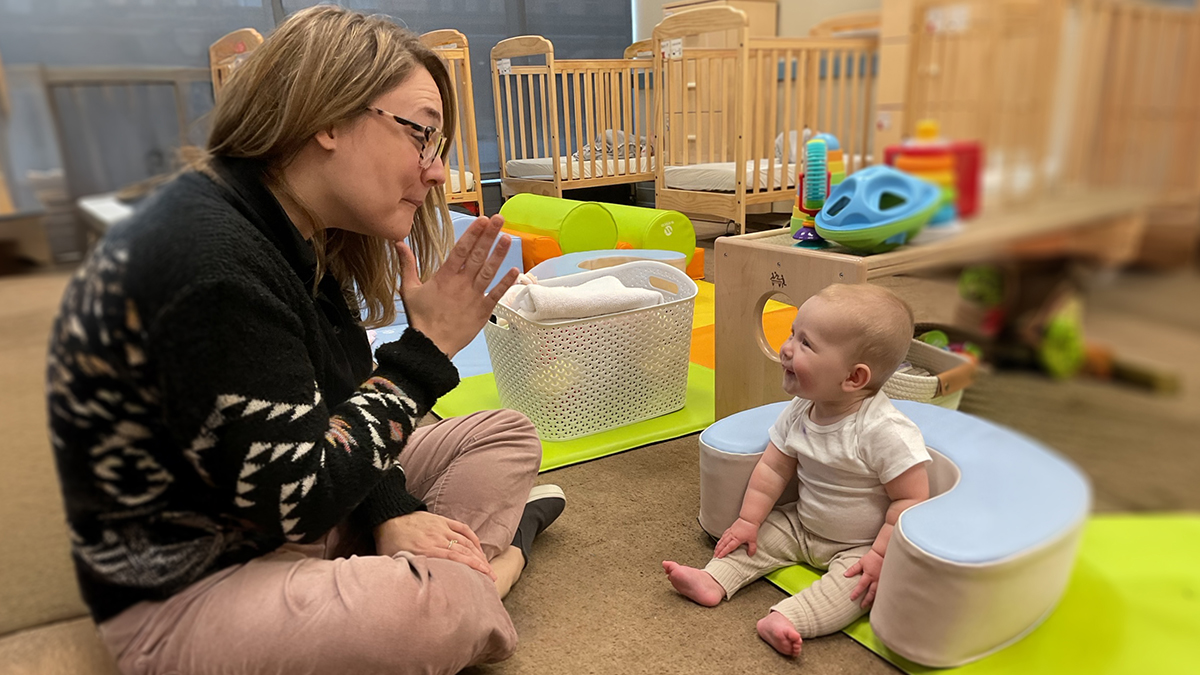 A child care provider teaches a baby sign language