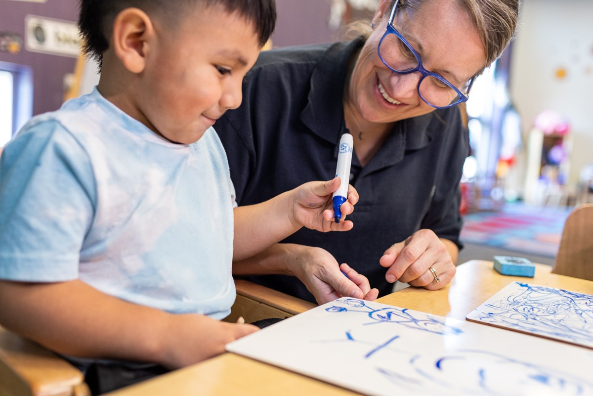 A man in a blue suit holds a microphone and speaks onstage at the 2026 Superintendents' Early Childhood Plan annual convening
